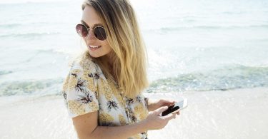 lady in floral blouse and sunglasses with phone in her hands