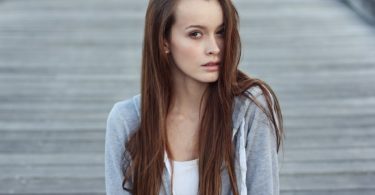 lady with brown hair in white top and grey vest