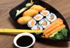 plate of salmon sushi with chop sticks and soya sauce