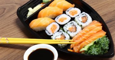 plate of salmon sushi with chop sticks and soya sauce