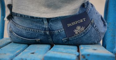 passport in back pocket of person sitting on blue bench