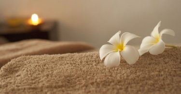 beige towel with white flower and candle