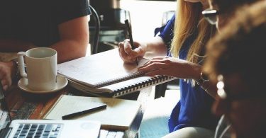two people with lots of papers on table