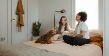 two ladies share the bed with a dog