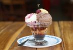 glace composée de trois boules de cerise sur une assiette blanche sur table en bois