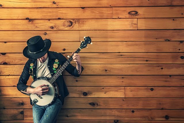 homme en chapeau jouant de la guitare