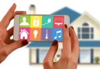 femme tenant une tablette devant une maison