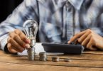 main tenant une ampoule sur des pièces de monnaie